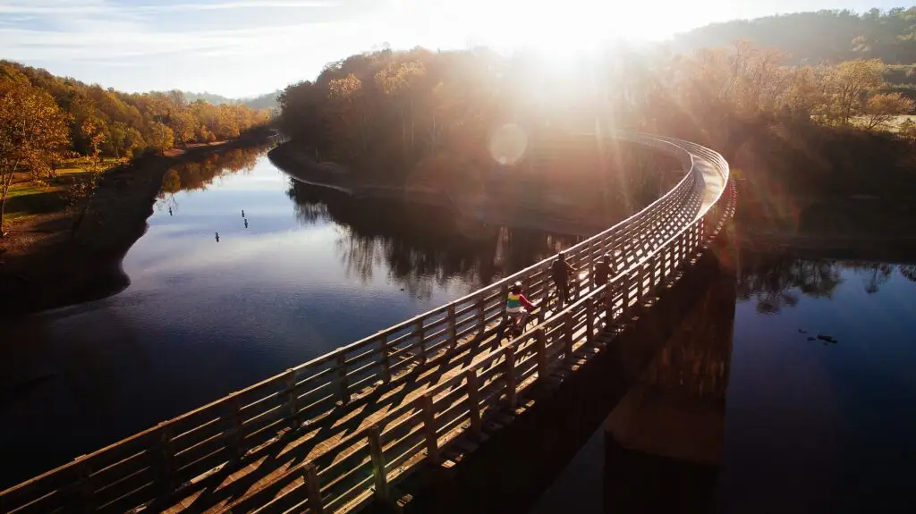 Aerial view of cyclists crossing a trestle on the Virginia Creeper Trail, surrounded by colorful fall foliage and wooded hills.