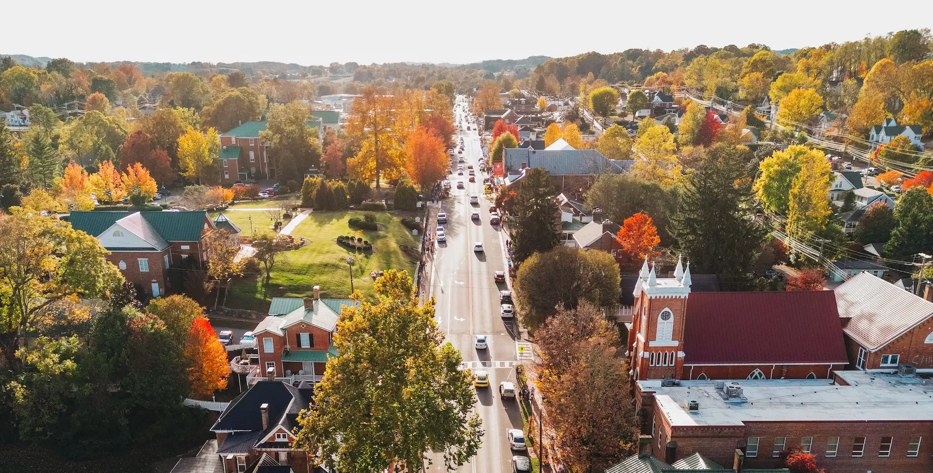 Aerial view of Main Street in downtown Abingdon, Virginia, surrounded by colorful fall foliage, historic buildings, and tree-lined neighborhoods.