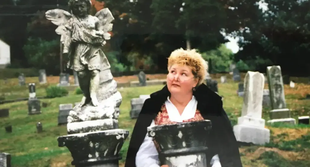 Donnamarie Emmert of Abingdon Spirit Tours stands beside an angel statue in Sinking Spring Cemetery in Abingdon, Virginia.